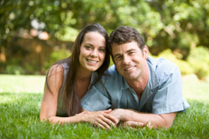 happy couple smiling outside while laying in the grass